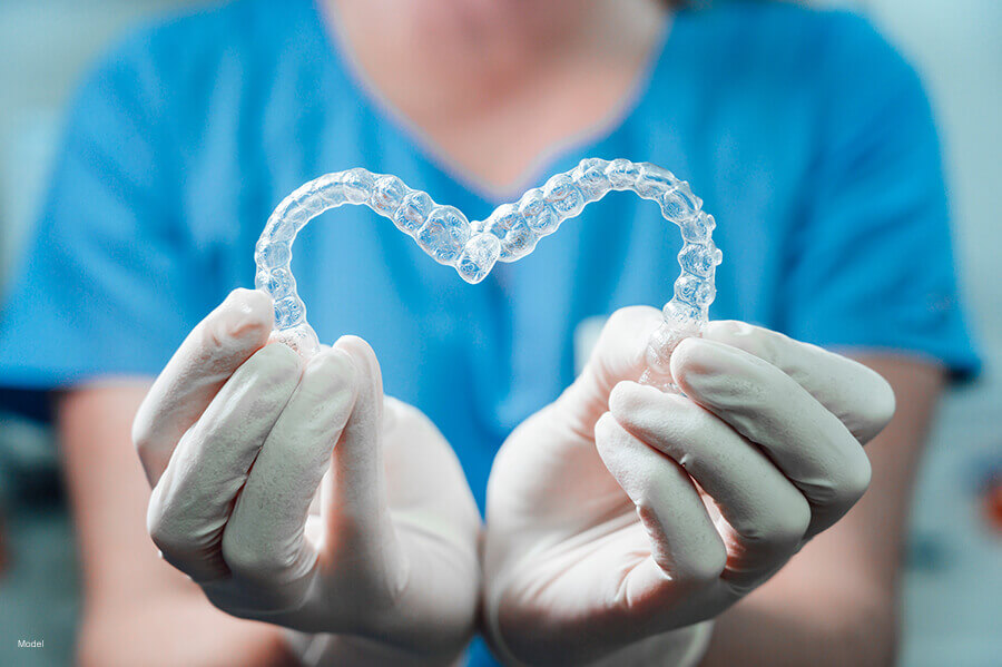 woman holding aligners in the shape of a heart