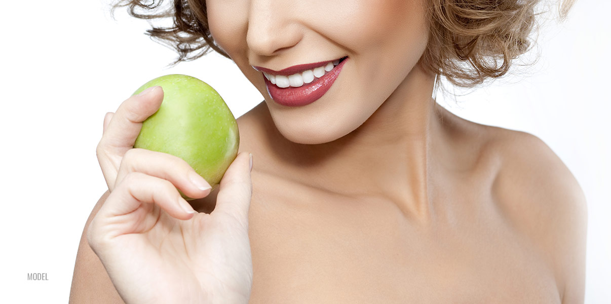 Women smiling and holding green apple in one hand