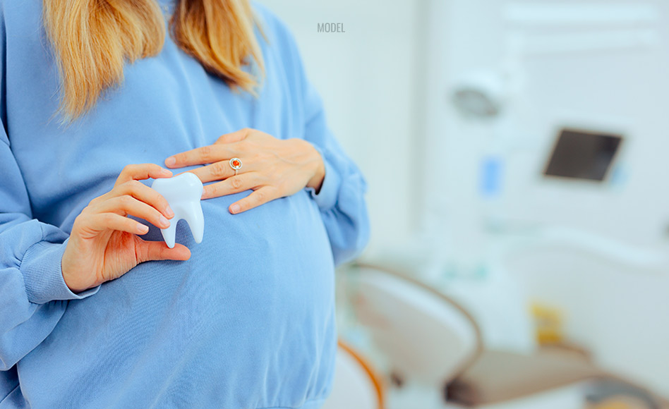 Pregnant women holding tooth at dental office